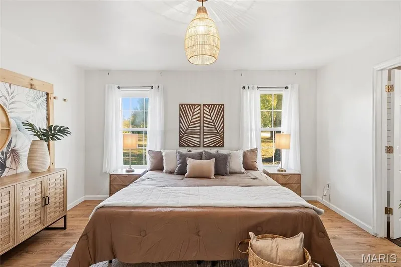 Primary Bedroom with Neutral-tones featuring wood-finish flooring, dual windows with grid detailing, and a textured pendant light fixture — 10341 Rose Lane, Foristell, MO 63348