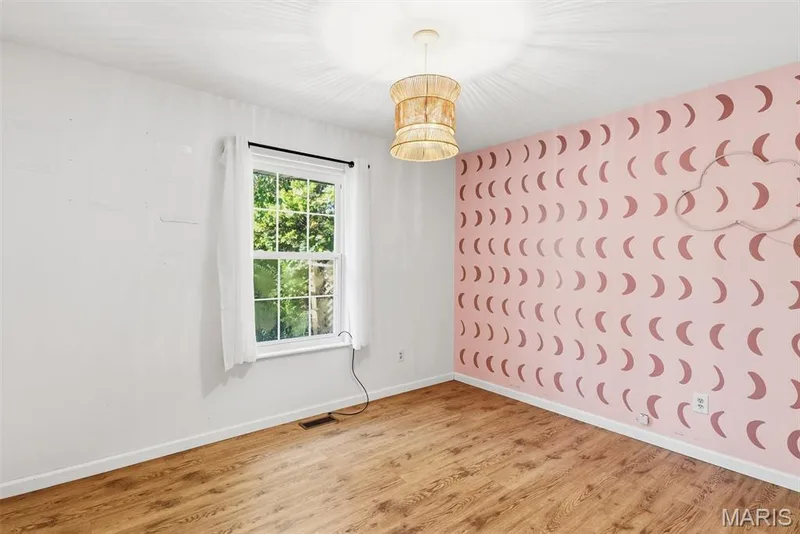Bedroom featuring Wood-finish flooring, multi-pane window with white trim, and a decorative pendant light fixture — 10341 Rose Lane, Foristell, MO 63348