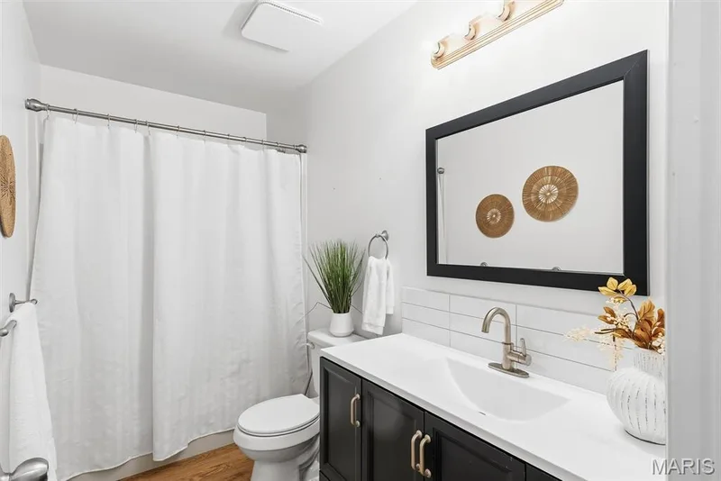 Vanity featuring a white countertop, under-mount sink, matte-finish hardware, and dark cabinetry — 10341 Rose Lane, Foristell, MO 63348