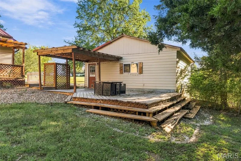 Exterior space featuring a wood pergola, tiered deck with lattice skirting, and horizontal siding — 10341 Rose Lane, Foristell, MO 63348