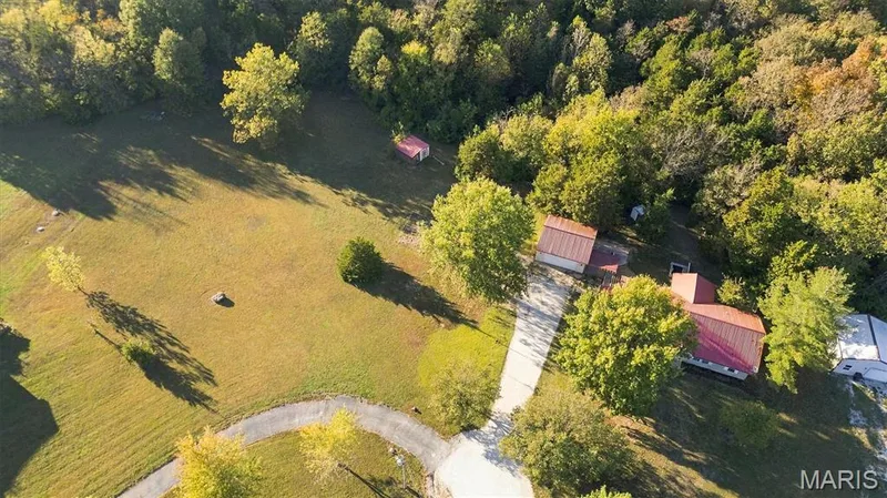 Expansive acreage featuring mature trees, a paved driveway, multiple detached structures, and open green space — 10341 Rose Lane, Foristell, MO 63348