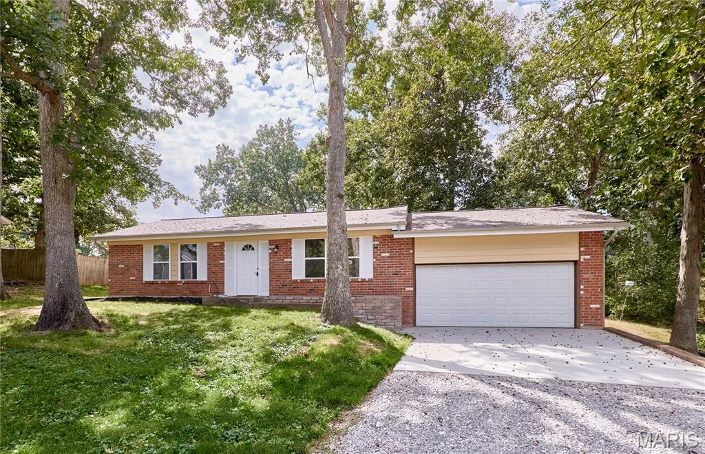 This home has all new windows and doors, a large front yard with mature trees.  Brick exterior with white shutters, a two-car garage with  an extra ceiling and a driveway with plenty of parking. — 408 Raymond Drive, O'Fallon, MO 63366