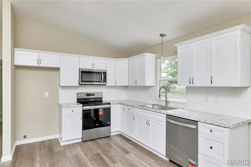 New kitchen, New cabinets, stainless steel appliances, light-toned countertops, tile backsplash. — 408 Raymond Drive, O'Fallon, MO 63366