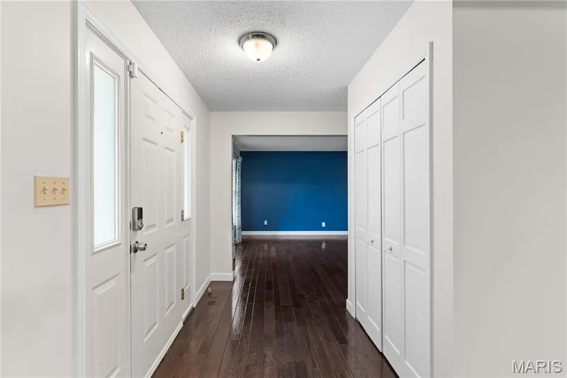 Entryway featuring a front door with glass sidelights, dark-toned wood-finish flooring, and built-in closet with double-panel doors — 838 Emerald Place Drive, St Charles, MO 63304