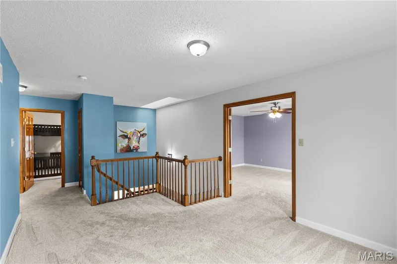 Staircase featuring a wooden banister and spindles, neutral carpeting, and a skylight — 838 Emerald Place Drive, St Charles, MO 63304
