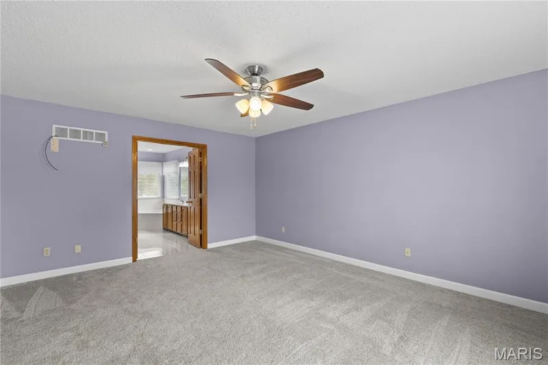 Room interior featuring neutral carpeting, a ceiling fan with integrated light fixture, and wooden door framing — 838 Emerald Place Drive, St Charles, MO 63304