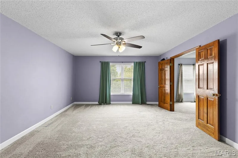 Room featuring wall-to-wall carpeting, a ceiling fan with integrated light fixture, a central window, and six-panel wood doors — 838 Emerald Place Drive, St Charles, MO 63304