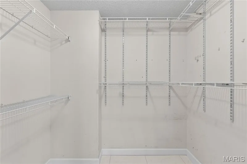 Walk-in closet featuring adjustable white wire shelving units and a wall-mounted track system — 838 Emerald Place Drive, St Charles, MO 63304