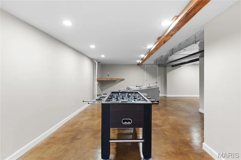 Finished lower level featuring stained concrete flooring, recessed lighting, exposed structural wood beams, and a built-in wall shelf — 838 Emerald Place Drive, St Charles, MO 63304
