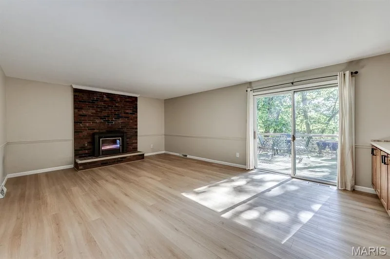This family room offers a wood burning fireplace, sliding door to the back deck, and natural light. — 3030 Woodlands, Wildwood, MO 63038