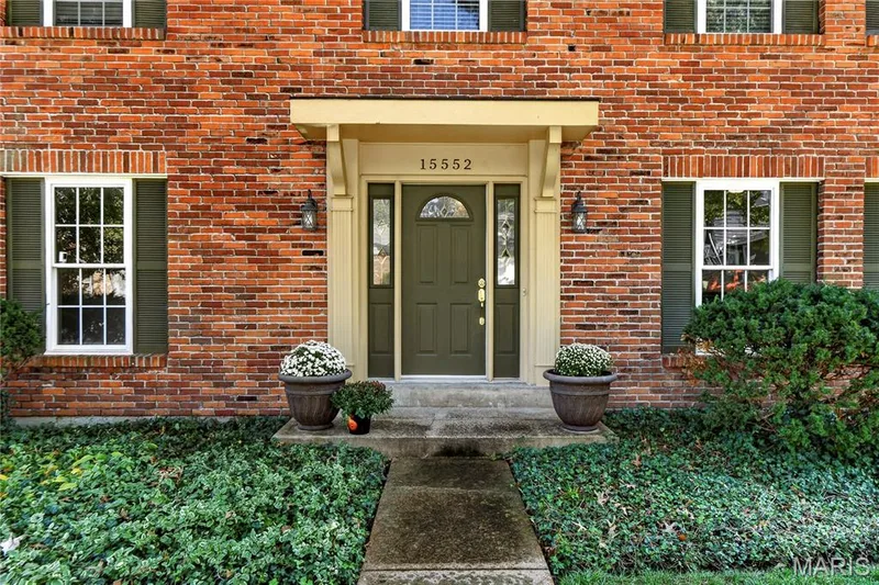 Traditional brick facade featuring a covered entryway, decorative shutters, multi-pane windows, and a paneled front door with sidelights — 15552 Chequer Drive, Chesterfield, MO 63017