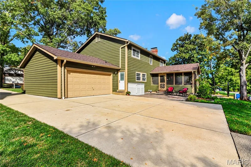 Exterior featuring horizontal siding, multi-vehicle concrete driveway, attached garage, screened-in porch, and mature trees — 15552 Chequer Drive, Chesterfield, MO 63017