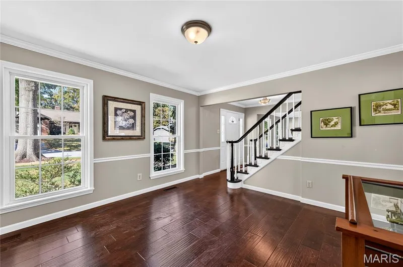 Hardwood flooring, chair rail molding, multi-pane windows, and a staircase with a black handrail — 15552 Chequer Drive, Chesterfield, MO 63017