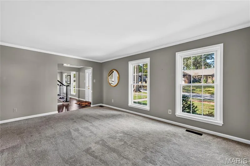 Living area featuring wall-to-wall carpeting, neutral interior paint, and two double-hung windows with exterior casing — 15552 Chequer Drive, Chesterfield, MO 63017