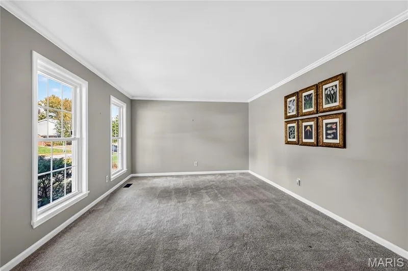 Neutral-toned interior space featuring wall-to-wall carpeting, dual double-hung windows, and crown molding — 15552 Chequer Drive, Chesterfield, MO 63017