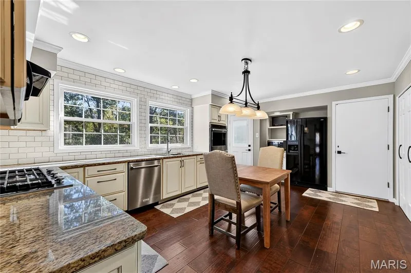 Kitchen featuring stone countertops, white subway tile backsplash, stainless steel appliances, built-in wall oven, and wood-finish flooring — 15552 Chequer Drive, Chesterfield, MO 63017