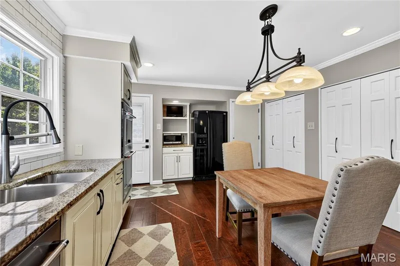 Kitchen featuring wood-finish flooring, stone-finish countertops, built-in wall oven, multi-light pendant fixture, and white cabinetry — 15552 Chequer Drive, Chesterfield, MO 63017