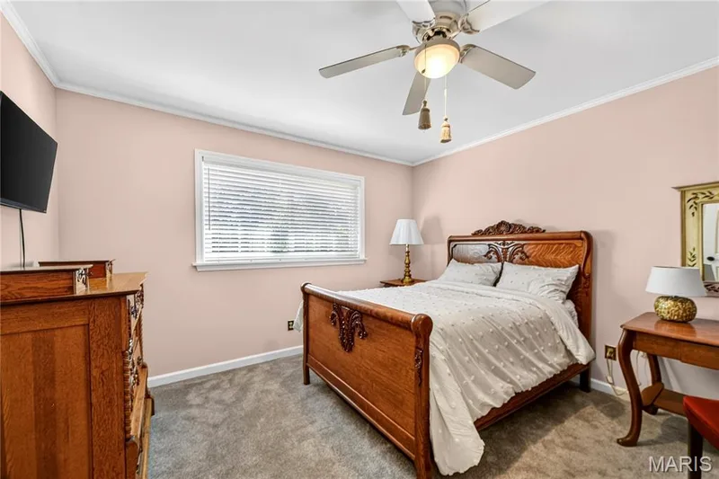 Bedroom featuring neutral wall paint, wall-to-wall carpeting, a multi-blade ceiling fan with integrated lighting, and a horizontal window with adjustable blinds — 15552 Chequer Drive, Chesterfield, MO 63017