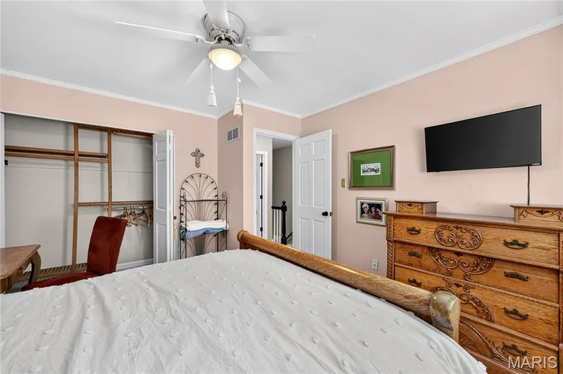 Bedroom featuring a ceiling-mounted light fixture with fan, crown molding, and a reach-in closet with double doors — 15552 Chequer Drive, Chesterfield, MO 63017