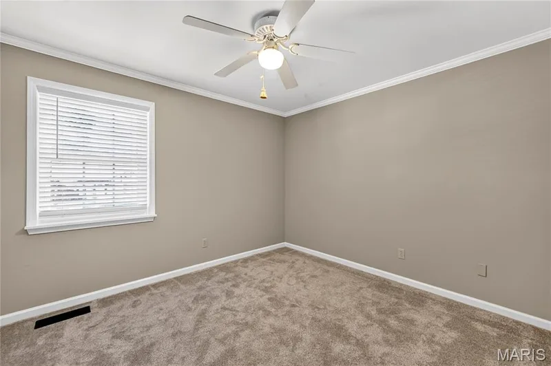 Room featuring neutral wall tones, plush wall-to-wall carpeting, crown molding, a multi-blade ceiling fan with integrated lighting, and horizontal window blinds — 15552 Chequer Drive, Chesterfield, MO 63017