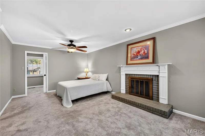 Fireplace with white mantle and brick surround, carpeted flooring, and ceiling fan with integrated lighting — 15552 Chequer Drive, Chesterfield, MO 63017