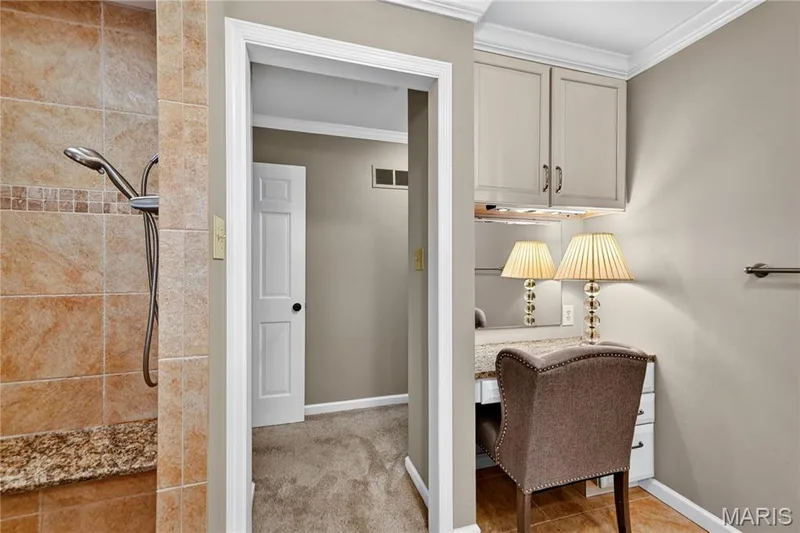 Shower area featuring stone-look wall tiles and a built-in stone-topped bench, paired with a custom vanity area including built-in cabinetry, a stone countertop, and crown molding — 15552 Chequer Drive, Chesterfield, MO 63017