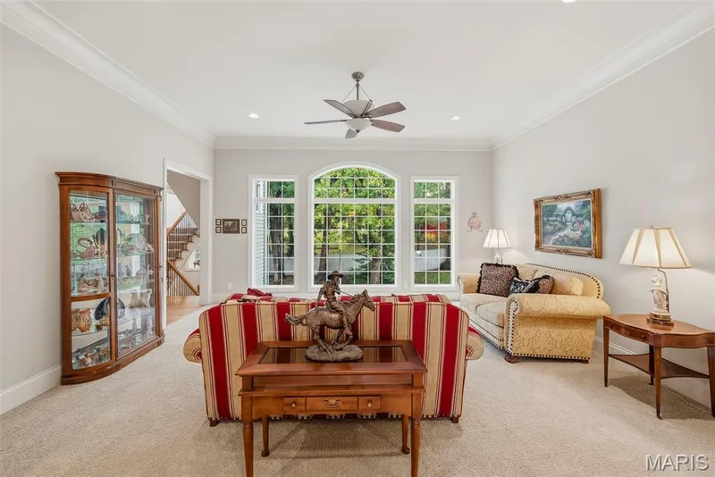 Great Room featuring high ceilings with crown molding, neutral carpeting, recessed lighting, a central ceiling fan, and large arched windows — 112 Castlewood Estates Drive, O'Fallon, MO 63368