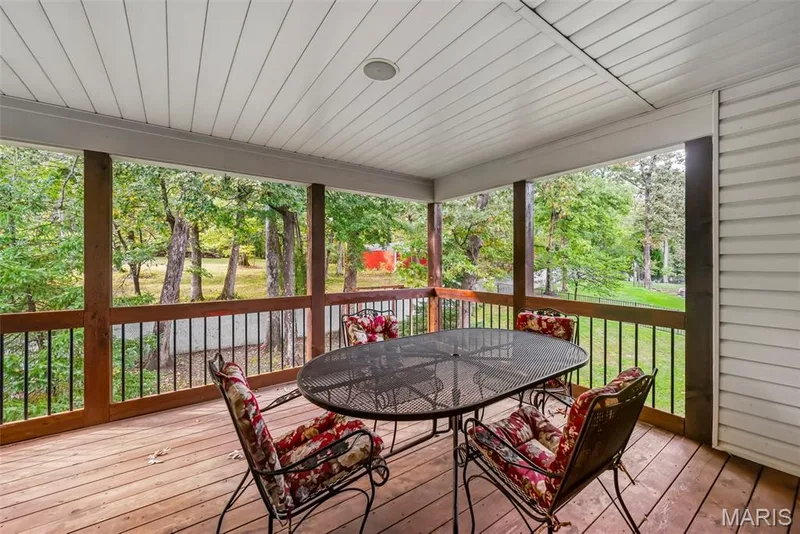 Covered deck featuring wood-finish decking, a white beadboard ceiling, and a wooden railing with metal balusters — 112 Castlewood Estates Drive, O'Fallon, MO 63368