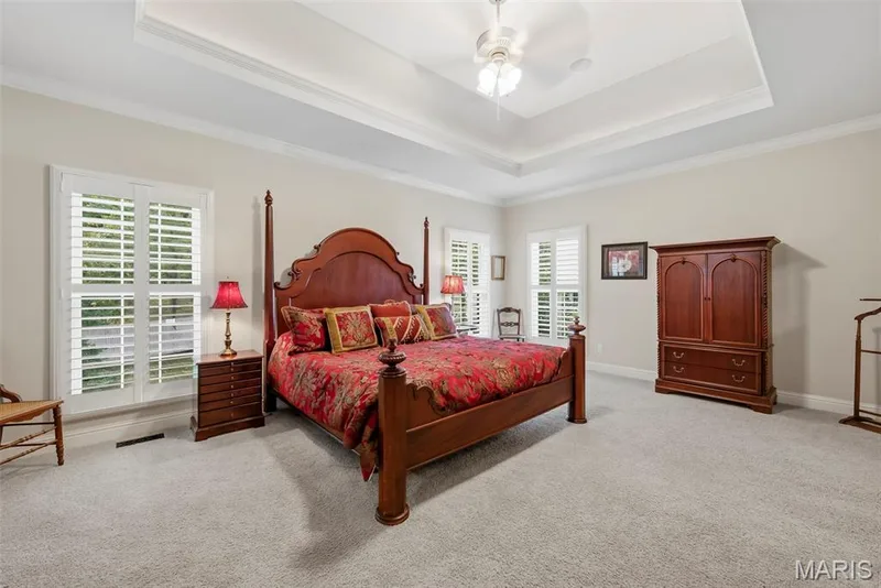 Spacious Primary Bedroom featuring a tray ceiling w/ inset lighting neutral wall tones, and plantation shutters — 112 Castlewood Estates Drive, O'Fallon, MO 63368