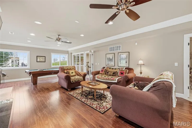 Lower Level featuring wood-finish flooring, dual ceiling fans, recessed lighting, and white-trimmed glass-paneled doors — 112 Castlewood Estates Drive, O'Fallon, MO 63368