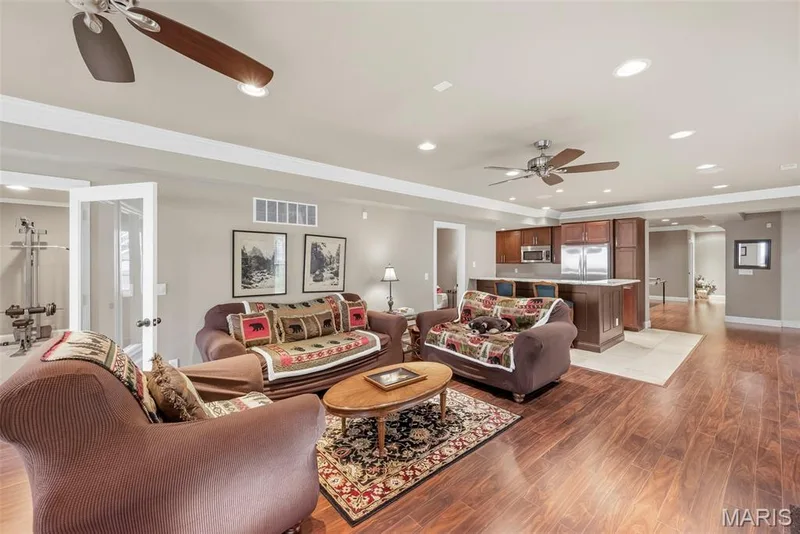Finished Lower Level featuring wood-finish flooring, recessed lighting, dual ceiling fans, and a kitchen island with stone countertop — 112 Castlewood Estates Drive, O'Fallon, MO 63368