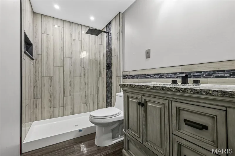 Granite-top vanity and wood-look tile floor in the lower bath. — 510 Keeney Drive, St Charles, MO 63304