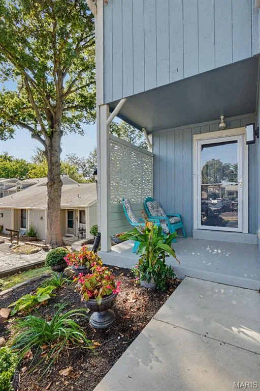 Covered entry with concrete patio, decorative privacy screen, exterior lighting, and landscaped garden bed — 81 Schooner Lane #1, Lake St. Louis, MO 63367