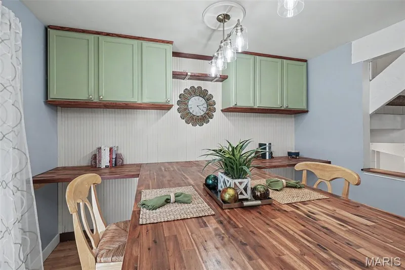 Custom Butcher Block Table with buffet style expansion upper cabinetry, beadboard wainscoting, and a multi-light ceiling fixture — 81 Schooner Lane #1, Lake St. Louis, MO 63367