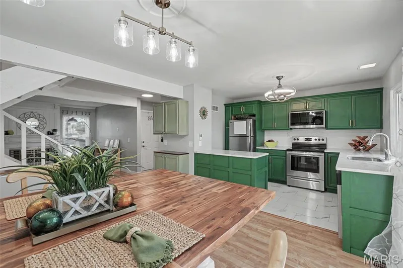 Kitchen featuring elegant green cabinetry, stainless steel appliances, white countertops, and a tile backsplash — 81 Schooner Lane #1, Lake St. Louis, MO 63367