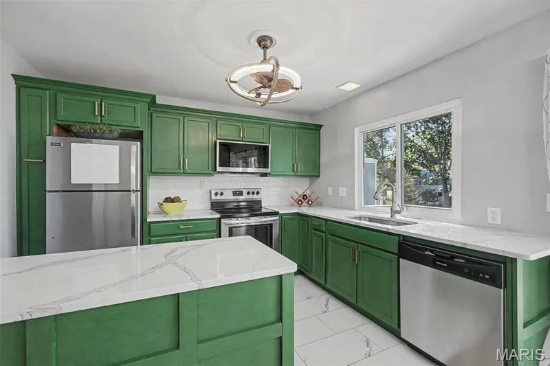 Kitchen featuring green cabinetry, stainless steel appliances, white countertops, and white tile flooring — 81 Schooner Lane #1, Lake St. Louis, MO 63367