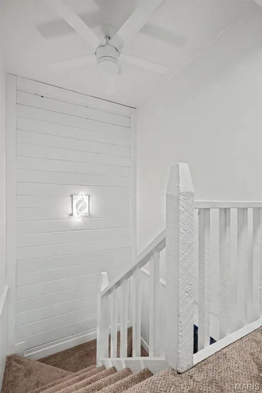 White ceiling fan, shiplap accent wall, wall-mounted light fixture, white wood handrail, and carpeted stairs — 81 Schooner Lane #1, Lake St. Louis, MO 63367