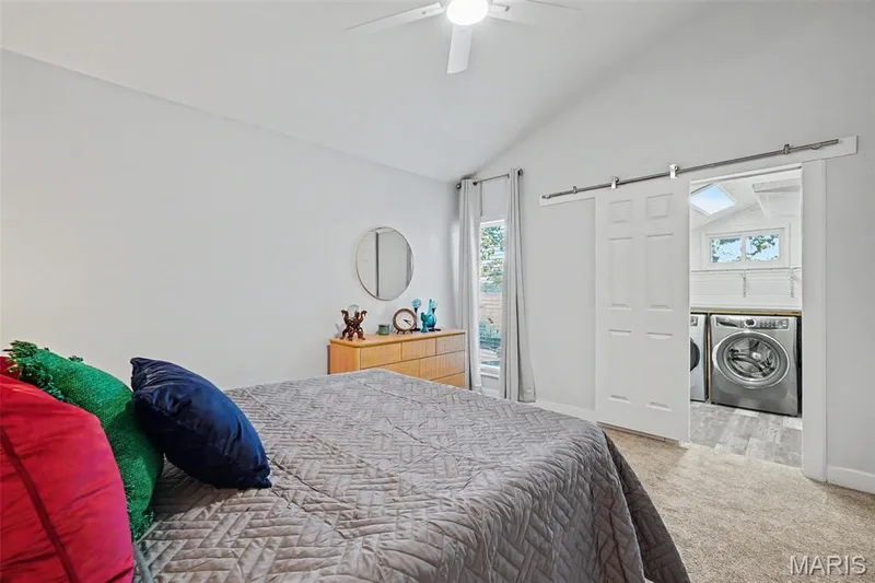 Vaulted ceiling with ceiling fan, white barn door, and dedicated laundry area with skylight — 81 Schooner Lane #1, Lake St. Louis, MO 63367