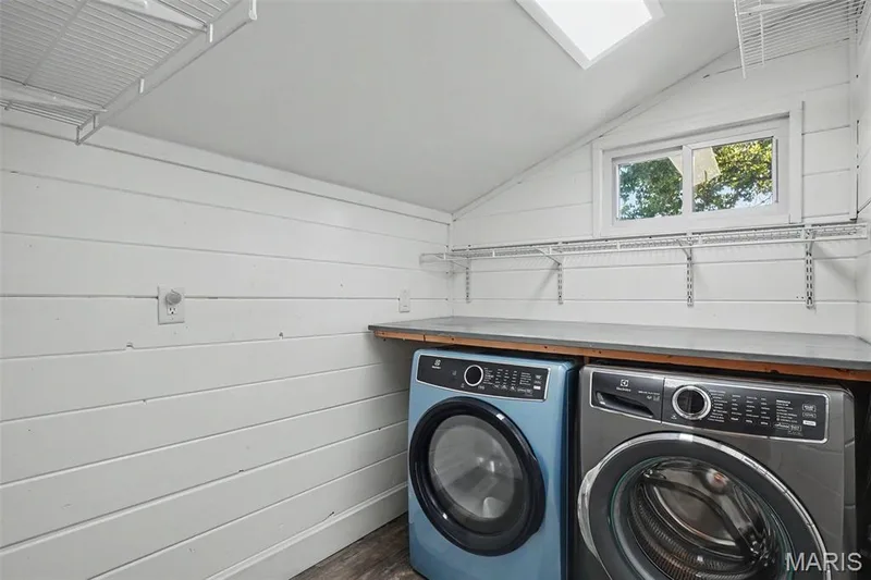 Slanted ceiling with a skylight, white shiplap walls, wood-finish flooring, built-in shelving, and a window — 81 Schooner Lane #1, Lake St. Louis, MO 63367