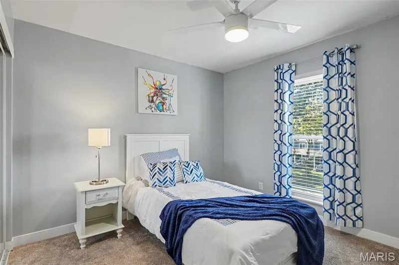 Light gray painted walls, recessed window with blinds, ceiling fan with integrated lighting, built-in closet with sliding doors, and carpet flooring — 81 Schooner Lane #1, Lake St. Louis, MO 63367