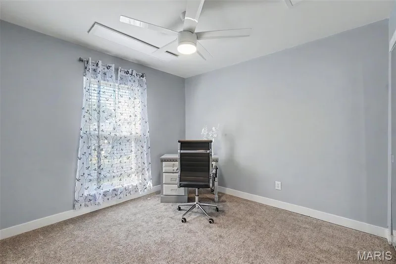 Carpeted room featuring a ceiling fan with integrated lighting, a window with blinds, and white trim — 81 Schooner Lane #1, Lake St. Louis, MO 63367