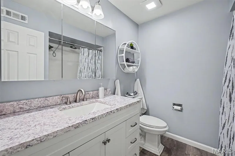 White vanity with brushed nickel hardware, integrated sink, and a patterned countertop — 81 Schooner Lane #1, Lake St. Louis, MO 63367