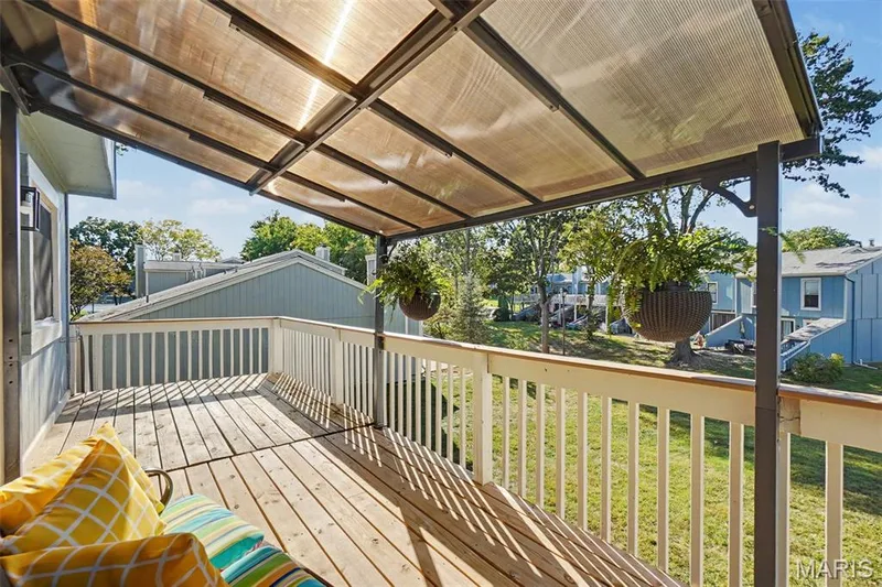 Expansive wood deck with a translucent overhead covering, white railing, and exterior siding — 81 Schooner Lane #1, Lake St. Louis, MO 63367