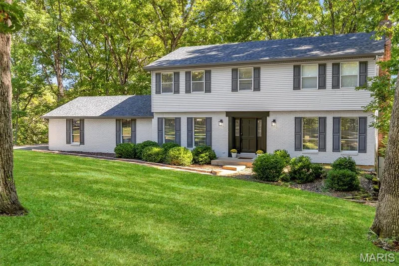 Two-story exterior featuring painted brick and siding, a gabled roofline, dark-toned shutters, and manicured landscaping — 1444 Eagle Ridge Road, Wildwood, MO 63038