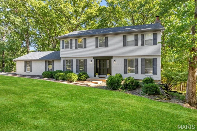 Two-story residence featuring light-toned horizontal siding, a painted brick facade, dark-toned shutters, and a central entry door with sidelights — 1444 Eagle Ridge Road, Wildwood, MO 63038