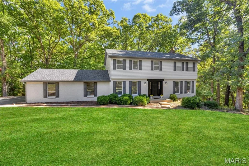 Two-story residence featuring a painted brick and siding exterior, grey shingled roof, dark window shutters, and mature trees on a spacious lot — 1444 Eagle Ridge Road, Wildwood, MO 63038