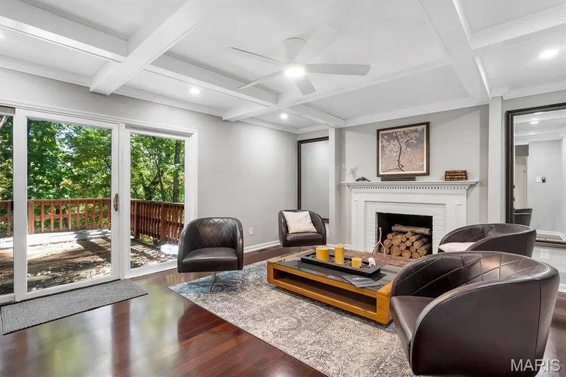 Coffered ceiling with integrated recessed lighting, wood-finish flooring, masonry fireplace with a white mantel, and sliding glass doors opening to an exterior deck — 1444 Eagle Ridge Road, Wildwood, MO 63038