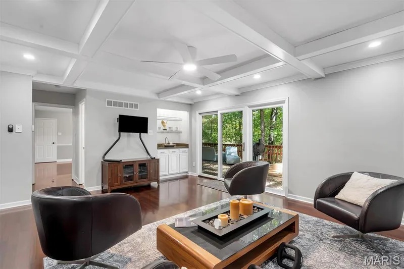 Coffered ceiling with integrated recessed lighting, dark wood-finish flooring, built-in wet bar with cabinetry and stone countertop, and sliding glass doors — 1444 Eagle Ridge Road, Wildwood, MO 63038