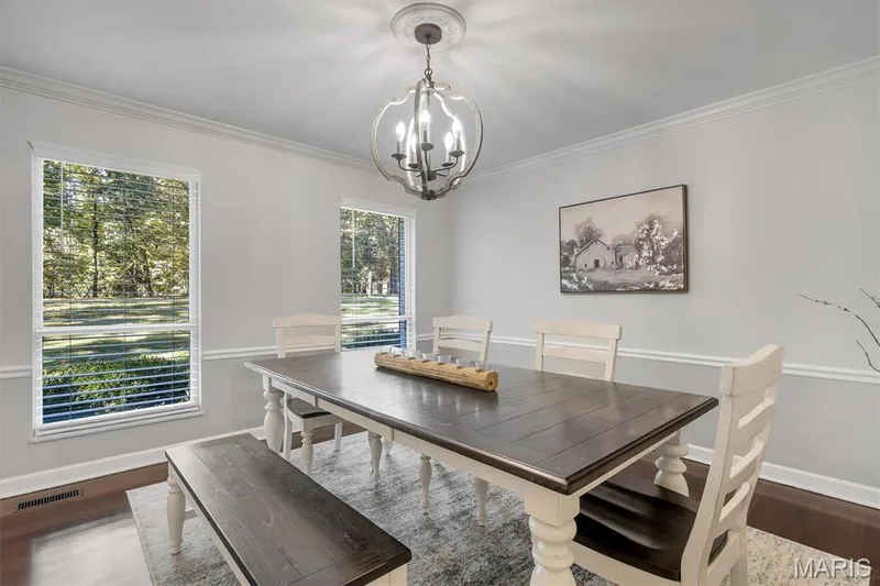 Dining area featuring wood-finish flooring, white chair rail molding, decorative ceiling medallion, and a metal orb chandelier — 1444 Eagle Ridge Road, Wildwood, MO 63038