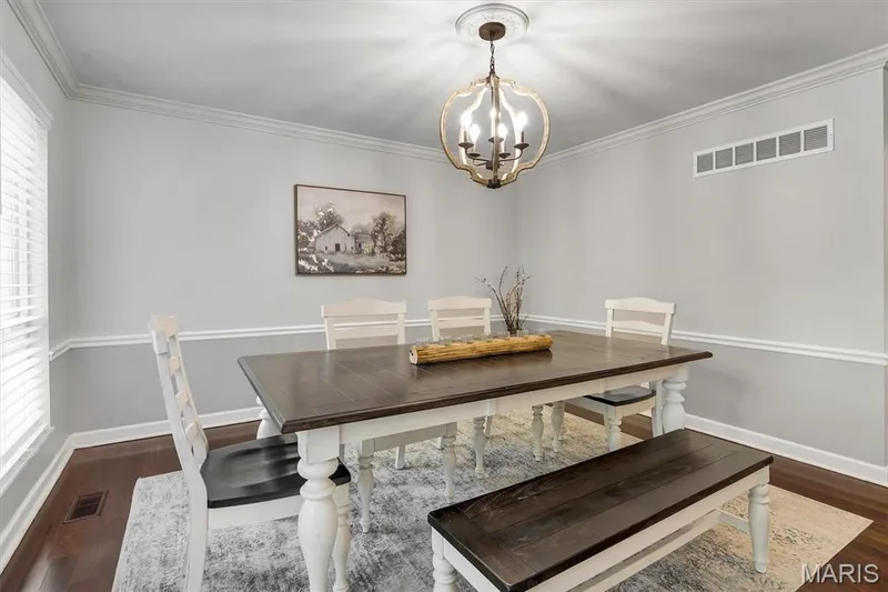 Dining area featuring dark wood-finish flooring, crown molding, chair rail trim, and a decorative metal chandelier — 1444 Eagle Ridge Road, Wildwood, MO 63038